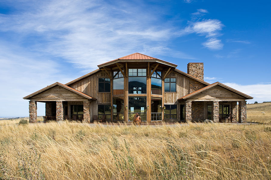 Large rustic wood and stone home with large glass windows