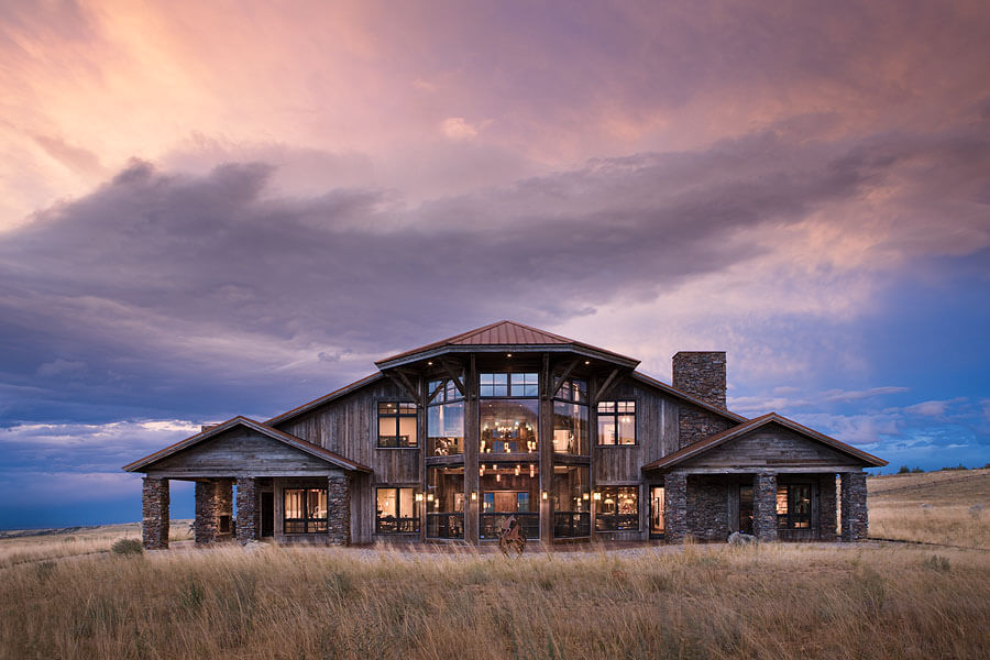 Large wood home with stacked stone pillars and large glass windows near Beartooth Mountains