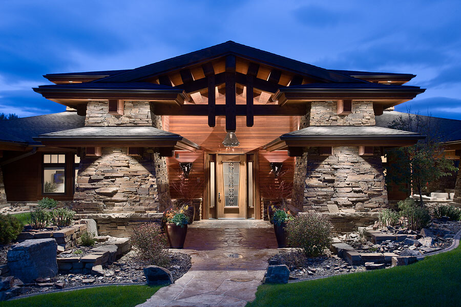 Home exterior with stone side walk leading through 2 large stacked stone piers to an Arts and Crafts-style wood and glass front door