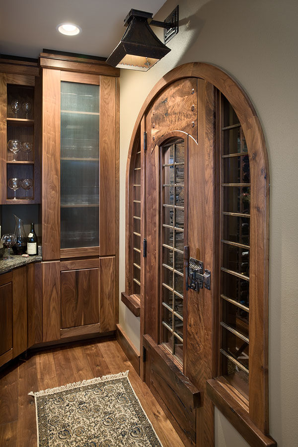 Handcrafted wood wine room door in Greene &amp; Greene-style with inset glass and hand-forged hardware