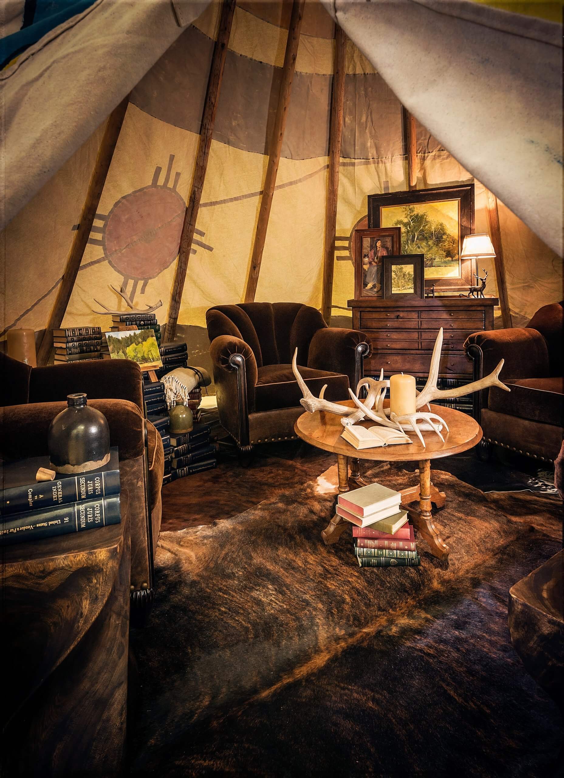 Interior of tipi with mohair armchairs, cow hide rug, coffee table with decorative antlers
