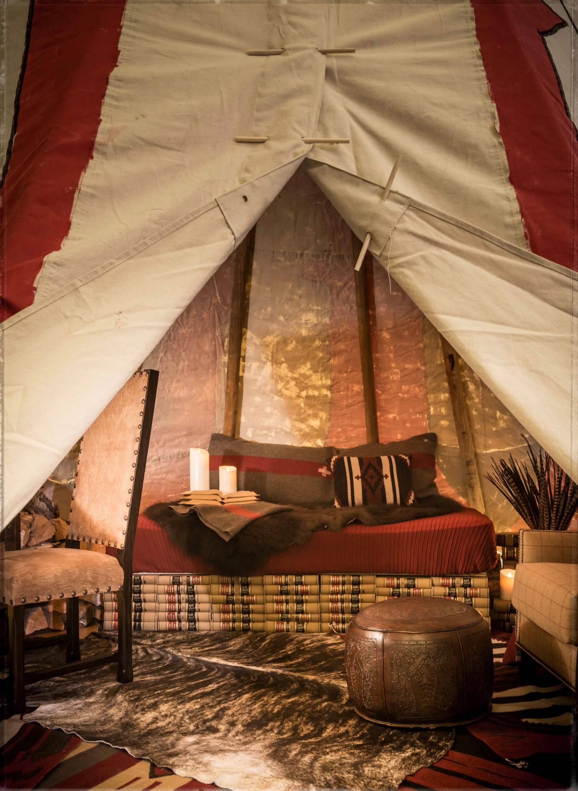 Interior of tipi with bed, chairs, cow hide rug, leather ottoman