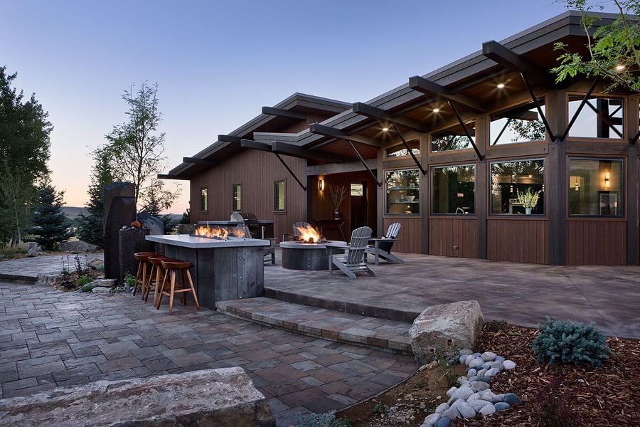 Stone patio with firepit, Adirondak chairs, and outdoor bar with fire feature.