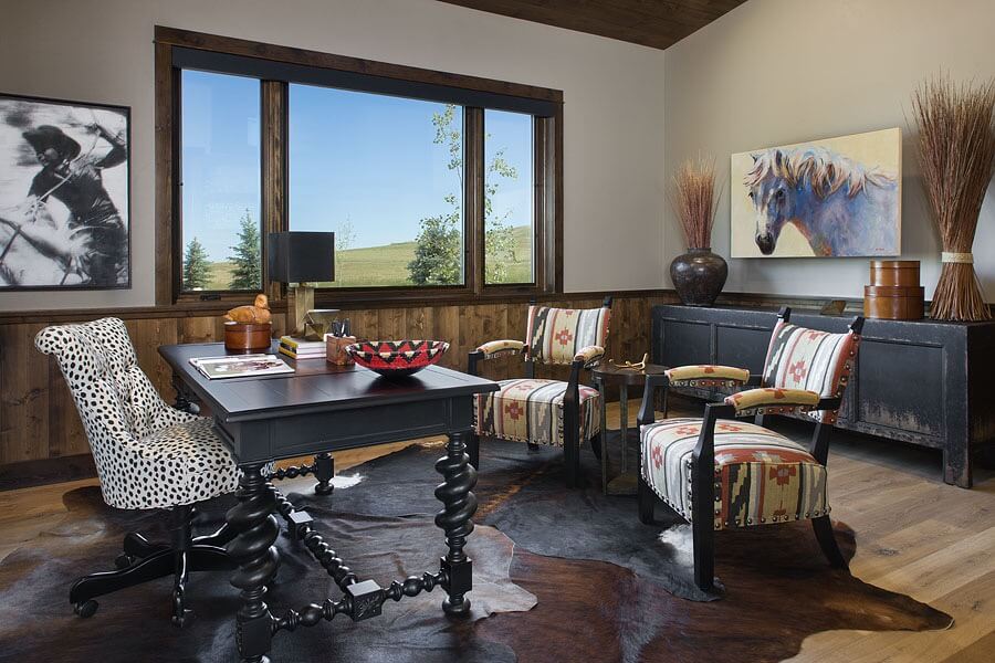 Home office with animal print office chair, black wood desk, hair on hide rugs, 2 guest chairs in geometric pattern.